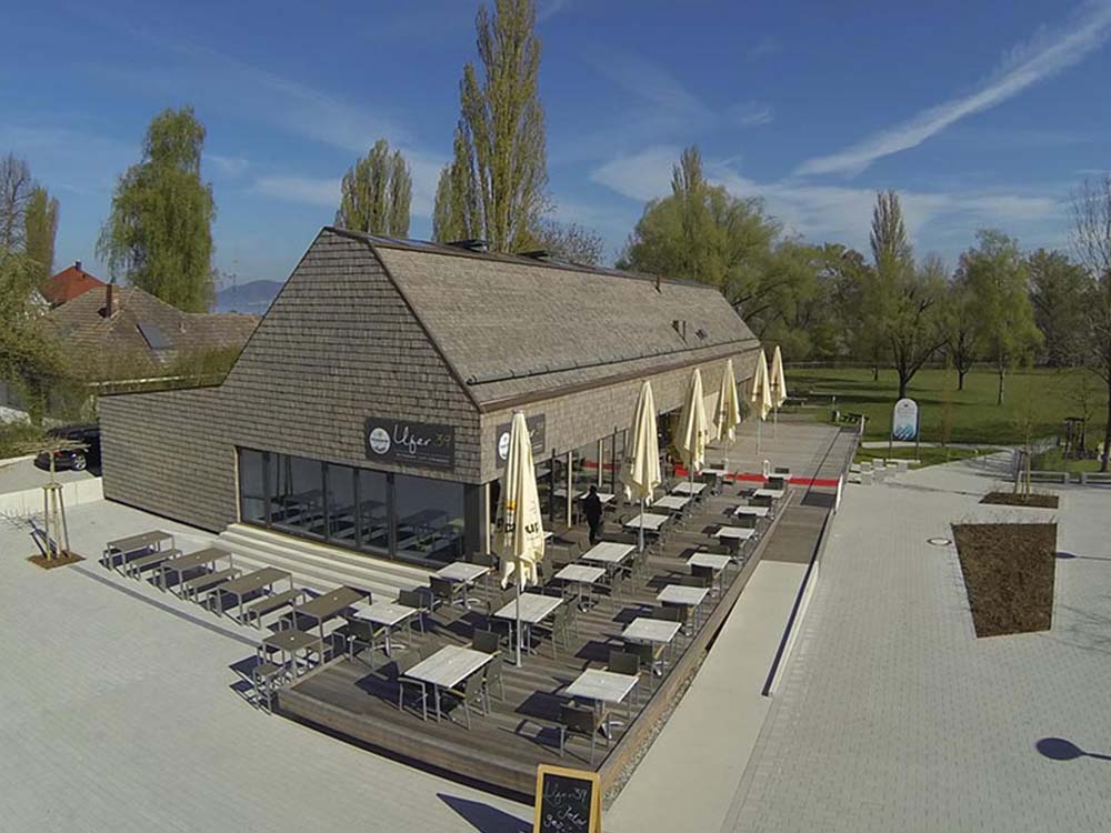 Strandbad Wallhausen am Ufer mit Restaurant, Holzfassade und DLRG‑Station — Strandbad, Restaurant, Badebetrieb, Versorgungsräume.