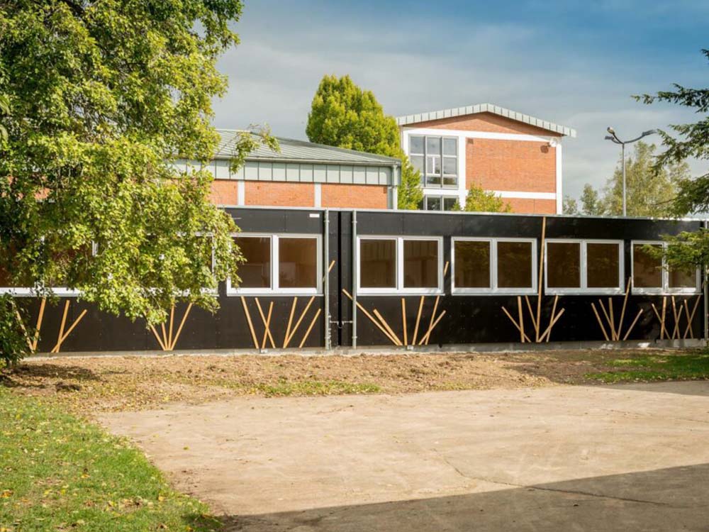 Klassenzimmer‑Modul in Holzbauweise mit integrierter Haustechnik nach Nachttransport und Aufstellung per Schwerlastkran — Klassenzimmer, Holzmodulbau, Haustechnik.