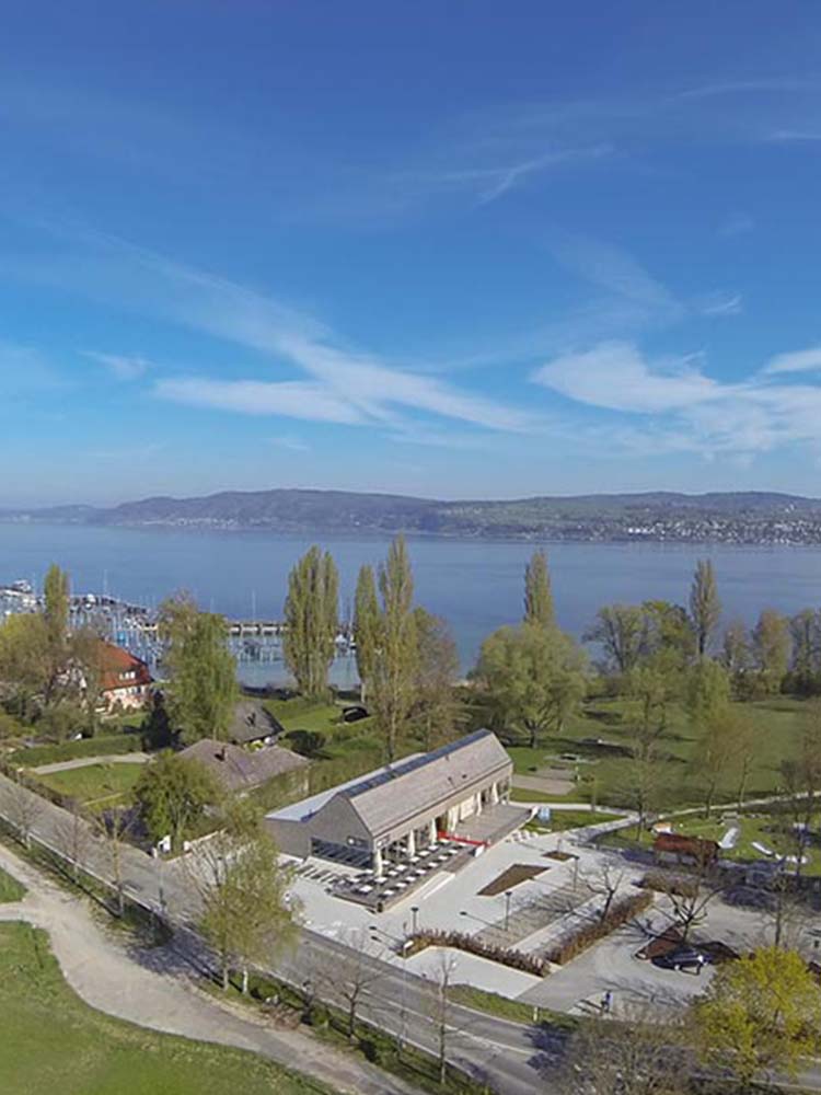 Strandbad Wallhausen am Ufer mit Restaurant, Holzfassade und DLRG‑Station — Strandbad, Restaurant, Badebetrieb, Versorgungsräume.