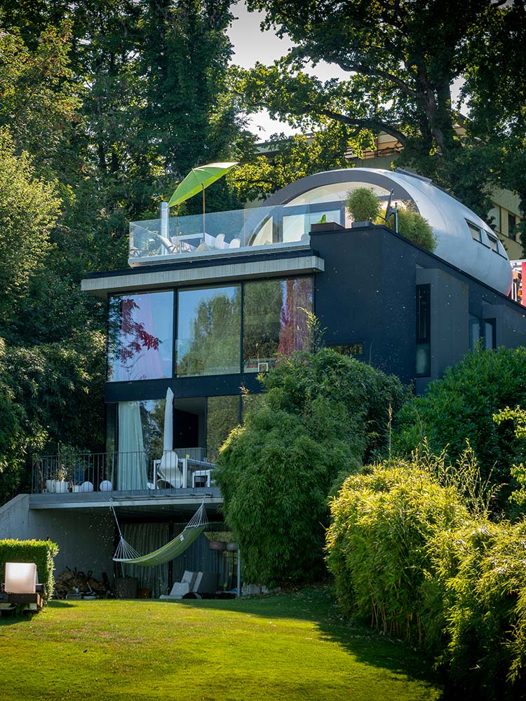 Wohn‑Ei „Parasit“ auf Flachdach am Bodensee — aufgesetzter Baukörper, nutzbare Dachfläche, Flachdach, Holzbauweise.