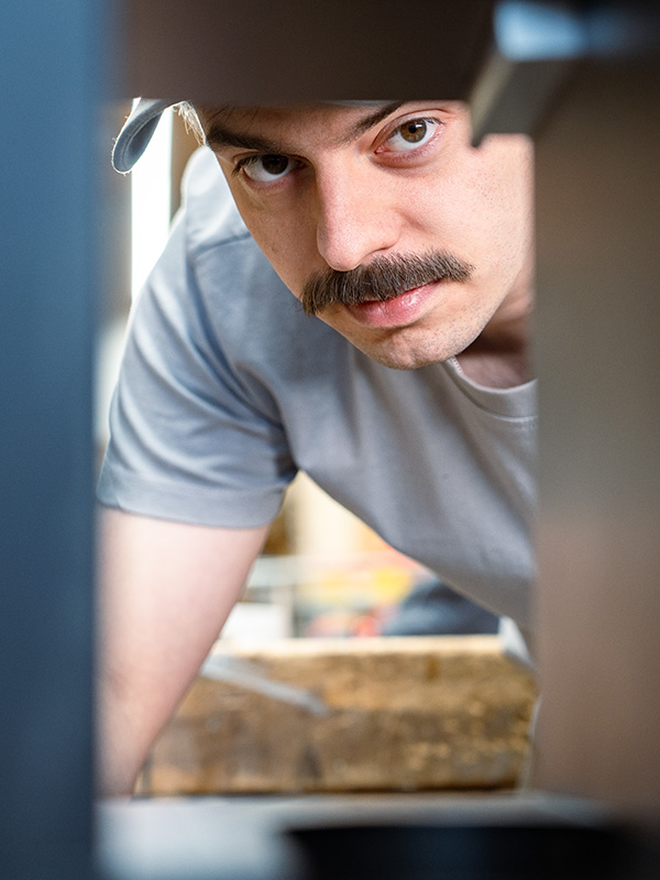 Ettwein‑Mitarbeiter prüft konzentriert ein Holzbauteil in Nahaufnahme — Ettwein, Job Holzbau, Ausbildung Zimmerer, Stellenanzeige Schreiner, Berufe Handwerk.