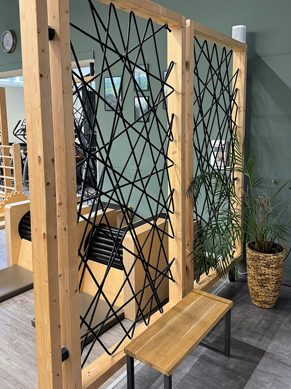 Modernes Fitnessstudio mit Trennwand aus Holz, schwarzen Seilen und kleiner Holzbank — Innenausbau, Objektbau, Einbauten in Büros, Ausstattung für Schulen.