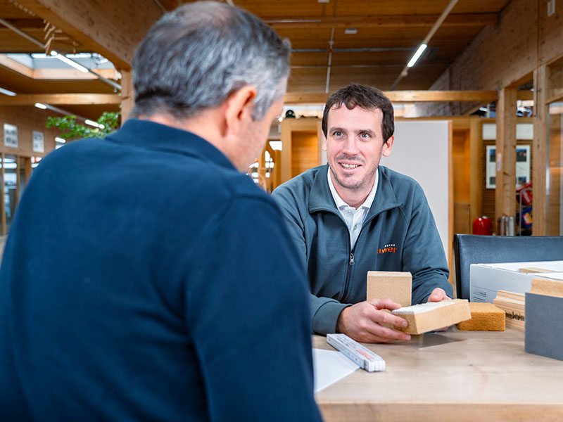 Steffen Ettwein berät Kunden mit Modell einer Akustikpaneele in Ettwein‑Räumen — Akustikpaneele von Lignotrend, Wandpaneele und Deckenpaneele.