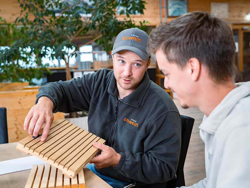 Ettwein Mitarbeiter berät Kunden zu einer Akustikpaneele – persönliche Beratung und Handwerksqualität aus der Zimmerei und Schreinerei Ettwein.