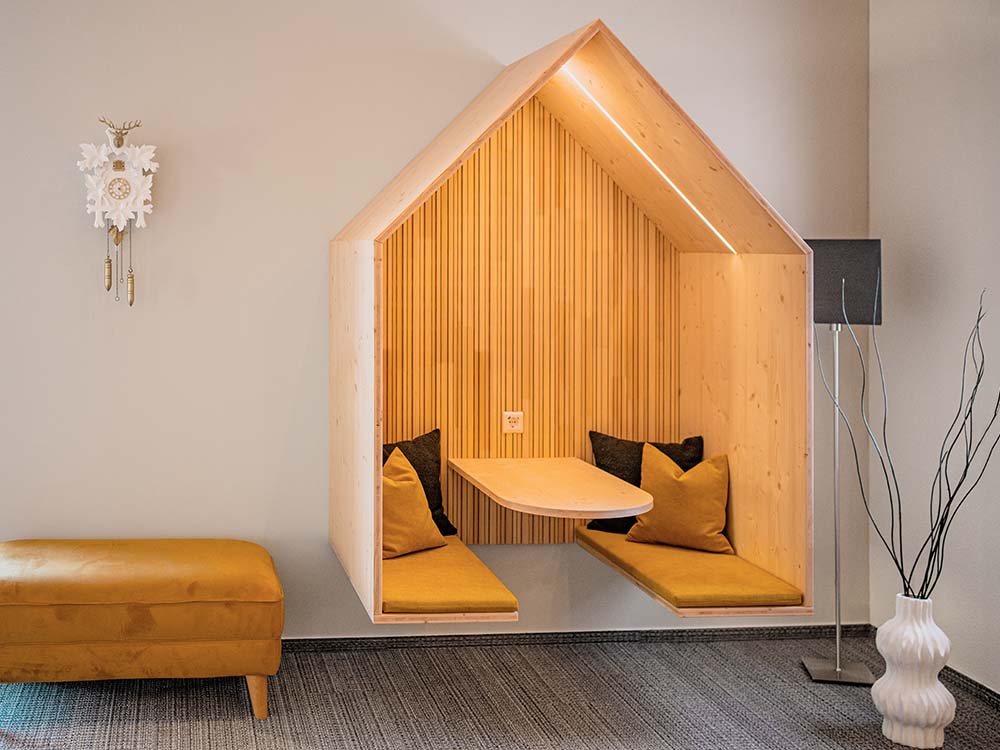 Referenz Innenausbau Gildner Werbeagentur: neue Decke, Bar aus Holz, Regal mit Beleuchtung, Akustikpaneele und beleuchtete Treppe.