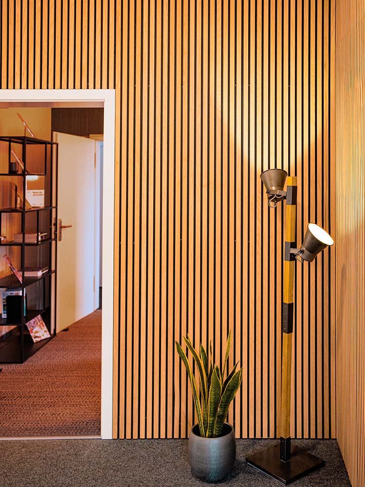 Referenz Innenausbau Gildner Werbeagentur: neue Decke, Bar aus Holz, Regal mit Beleuchtung, Akustikpaneele und beleuchtete Treppe.